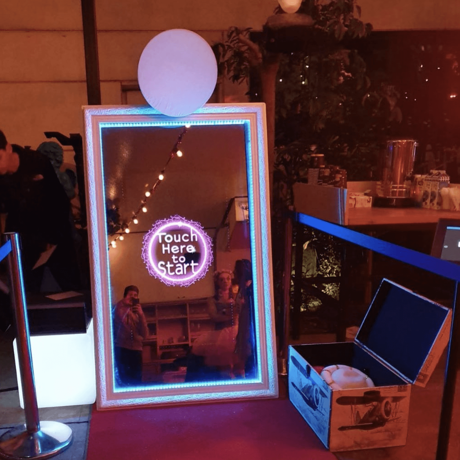 Tall rectangular photo booth in the style of a mirror. A wedding monogram is lit up in the center.