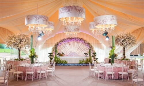Three chandeliers displayed in wedding venue with ceilings featuring draped fabric